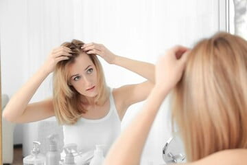 mujer mirándose el pelo en el espejo